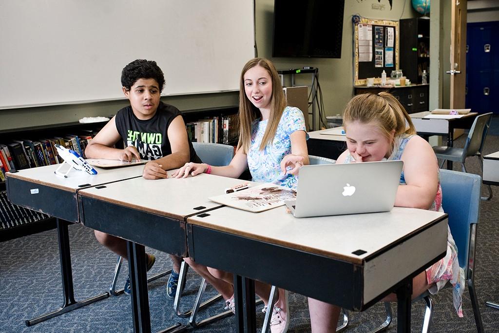 A student teaching two children in a classroom